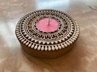 Side view of intricately carved wooden candle stand designed to hold a candle at its center.