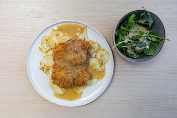 Chicken schnitzel with gravy and salad on the side.