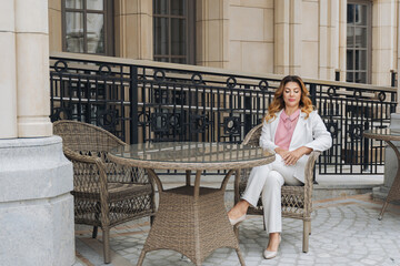 Woman Sitting Patio Chair Table White Suit Building