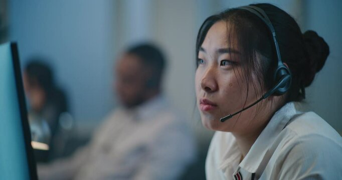 Call center office of emotional support line: Portrait of stressed Asian female hotline operator in headset consulting person on call, providing psychological help. Online mental health professional.