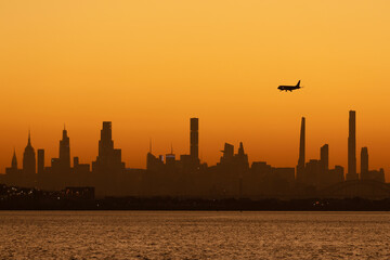 Airplane landing over the Manhattan skyline at sunset