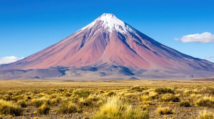 Perfectly symmetrical volcano with a snow-capped peak in a dry, grassy plain