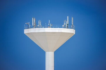 cellular antenna in top of water tower, white against the clear blue sky