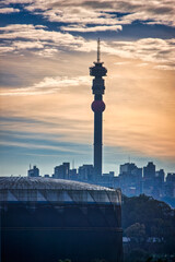 Fototapeta premium sunset over Hillbrow telecommunications Tower in city skyline in Johannesburg. surrounded by downtown buildings in Johannesburg, South Africa at down dusk late evening