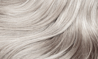 Blond hair close-up as a background. Women's long blonde hair. Beautifully styled wavy shiny curls....