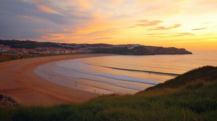 Golden sunset over tranquil beach in northern Spain with surfers enjoying the waves and a picturesque village nearby