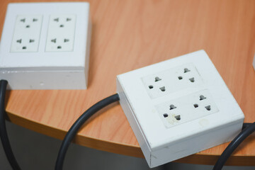 two white electrical power strips placed on a wooden surface. Each power strip has two sets of...