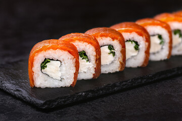 Japanese rolls, Philadelphia sushi with salmon and cream cheese on a black background.