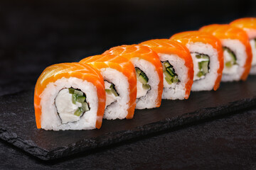 Japanese rolls, Philadelphia sushi with salmon and cream cheese on a black background.