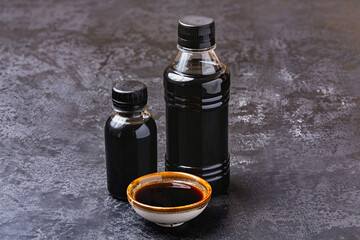 Soy sauce in a plastic bottle and sauce boat on a black background.