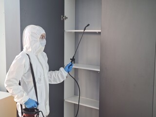Professional pest control technician disinfects a cabinet in a residential space to ensure safety and cleanliness concept