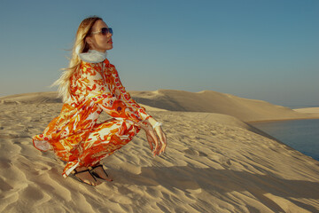 A girl poses on the dunes in the "Inland Sea" of Khor Al Adaid in the rays of the setting sun in Qatar