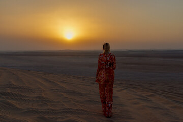 A girl poses on the dunes in the "Inland Sea" of Khor Al Adaid in the rays of the setting sun in Qatar