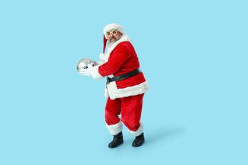 Funny Santa Claus with disco ball dancing on blue background