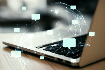 Speech bubbles and connection network over a laptop keyboard, representing online communication and...