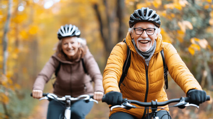 Naklejka premium Enjoying vibrant autumn day, elderly man and woman ride bicycles through colorful forest. Their smiles reflect joy and vitality amidst beautiful fall scenery