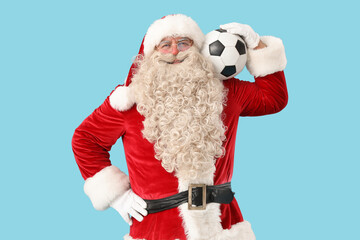 Santa Claus with soccer ball on blue background