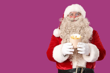 Santa Claus with tasty french fries on purple background
