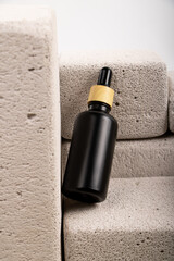 Matte Black Dropper Bottle with Greenery on Stone Blocks for Skincare and Aromatherapy Branding
