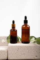 Amber Glass Dropper Bottles with Greenery on Stone Blocks for Natural Skincare and Aromatherapy
