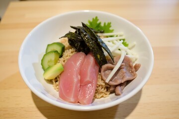 Delicious tuna rice bowl with fresh vegetables and seaweed garnish in white bowl