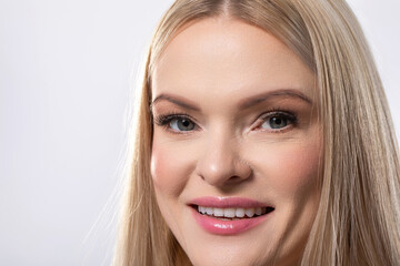 A Smiling Woman with Long Blonde Hair Posing Beautifully in a Bright Studio Setting