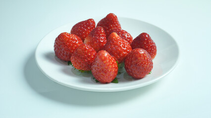 Red organic strawberries displayed on a white plate