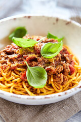 Spaghetti bolognese and fresh Basil o bright background. Close up.