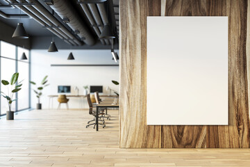 Modern office interior with blank poster on wooden wall, open workspace with desks and chairs in background. Cozy and bright environment. 3D Rendering