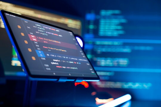 Programmer manually working with program code on a computer at night in a data center and technology concept.
