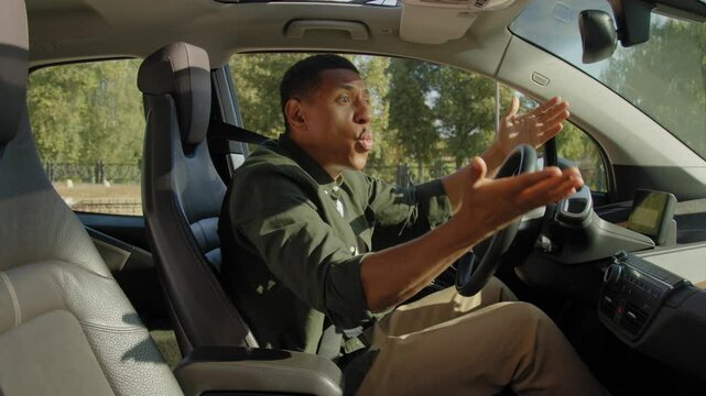 Shocked black male driver driving car in city traffic , making emergency brake and avoiding car accident on road, expressing irritation and frustration.