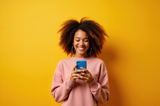 Smiling woman using smartphone against vibrant yellow background