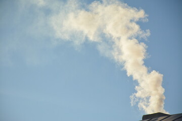Smoke from a chip pipe against a blue sky