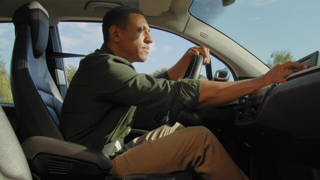 Attractive black man driver in smart casual clothes choosing travel destination using gps navigator map on trip computer, searching for best route while driving car on business road trip.