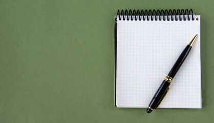 Top view of a notepad and pen on a green background. A place to record. The banner.