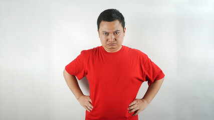 A young Indonesian man wearing a red t-shirt with a frown facing forward