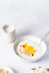 Fresh porridge on nut milk with baked oranges, orange jam and nuts on a gray background. Healthy breakfast, healthy food