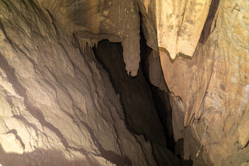 The cave is dark and has a lot of rock formations. The walls are covered in dirt and the ceiling is made of rock.