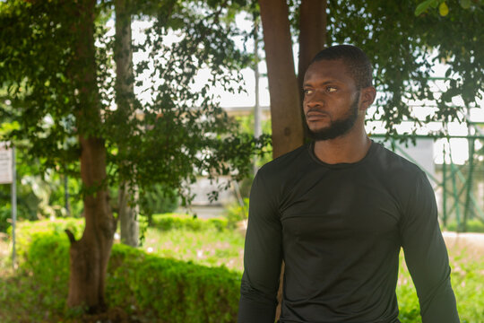 Athletic young man in urban park on a sunny day in the beginning of fall and harmattan with copy space