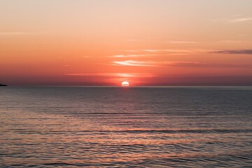 Obraz premium Sunset Over Calm Sea with Vibrant Colors and Reflections