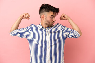 Young caucasian man isolated on pink background doing strong gesture