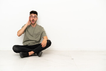 Young caucasian man sitting on the floor isolated on white background with surprise and shocked facial expression