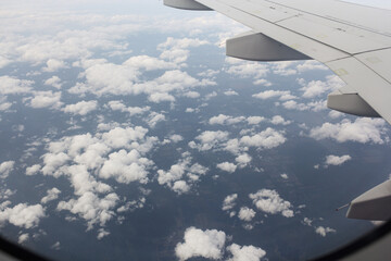 Sparse cumulus clouds under the wing of an airplane.