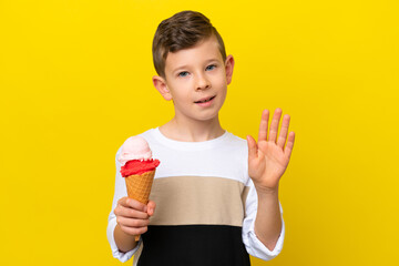 Little caucasian boy with a cornet ice cream isolated on yellow background saluting with hand with...