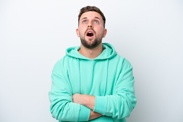 Naklejka premium Young caucasian man isolated on white background looking up and with surprised expression