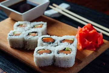 A plate of sushi with a dipping sauce and chopsticks