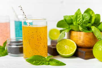 Diet detox cocktail with basil and chia seeds in a glass jar and a glass on a textured background....