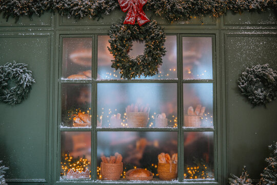 Holiday bakery window display with frosted wreaths and festive decorations