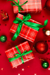 Holidays gifts boxes wrapped in red paper with green ribbon bow on red background.