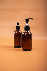 Amber Glass Pump and Dropper Bottles for Skincare and Essential Oils on Neutral Background
